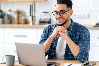 man sitting at a table looking at a laptop