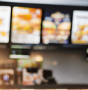 Six blurry overhead menus hang in a fast food restaurant.  
